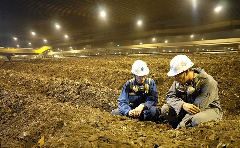 Workers examining material inside Edmonton’s composting hall